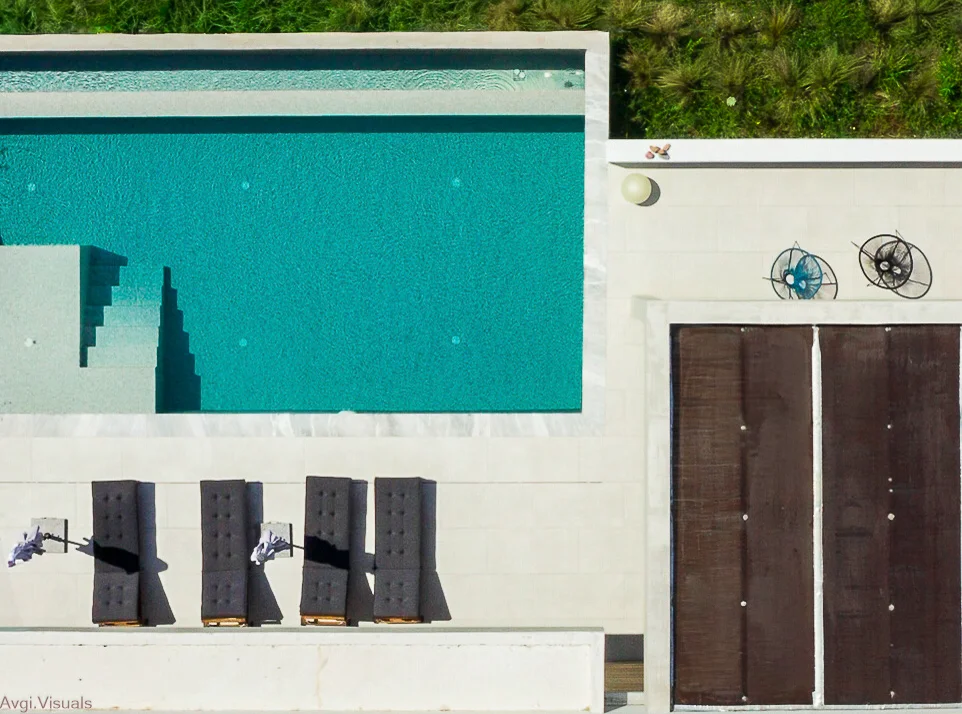 Top-down aerial photograph of a modern villa swimming pool and sun deck by Avgi Chourlia