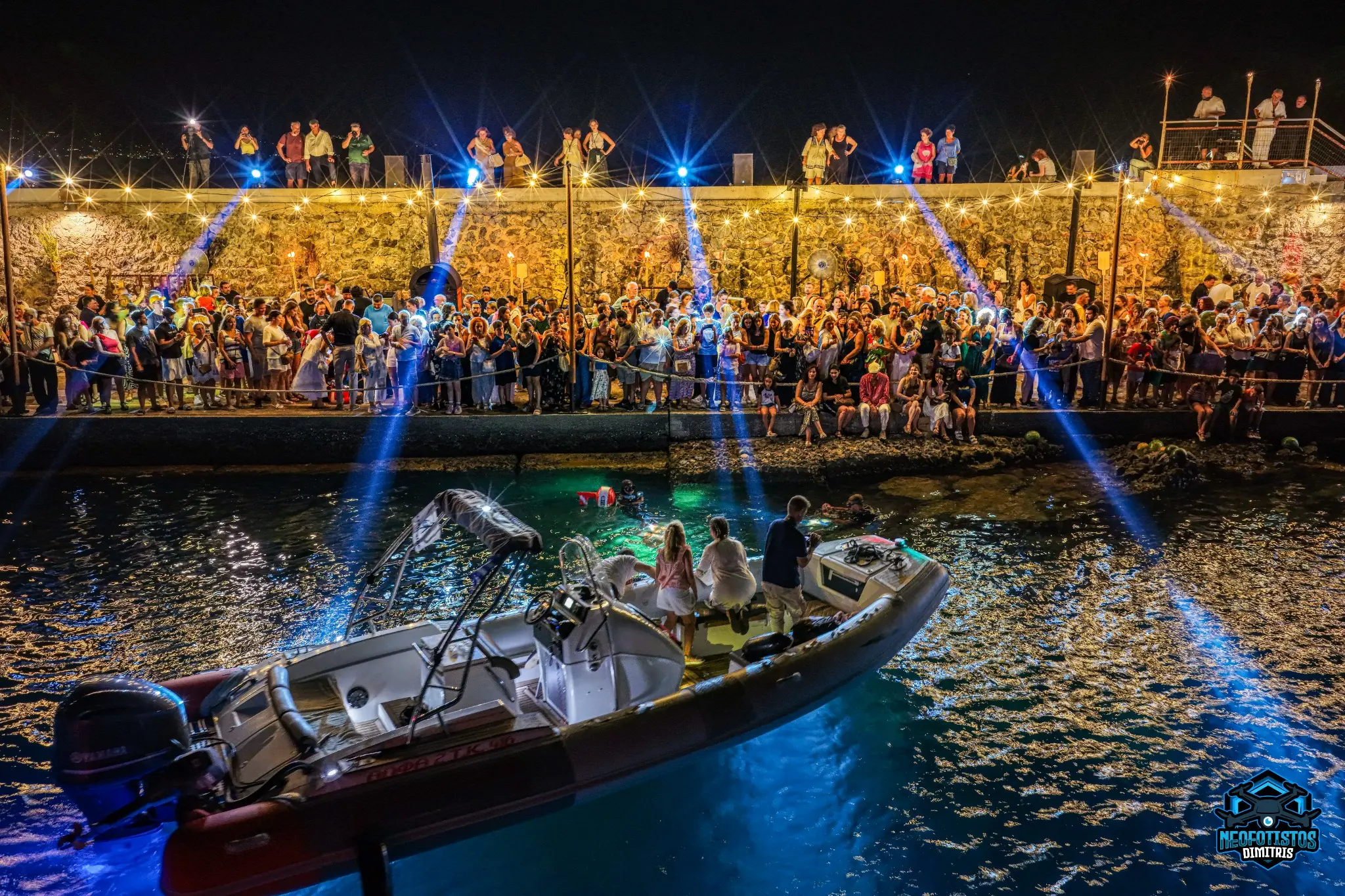 Night aerial coverage of a waterfront event with boats and spectators by Dimitris Neofotistos