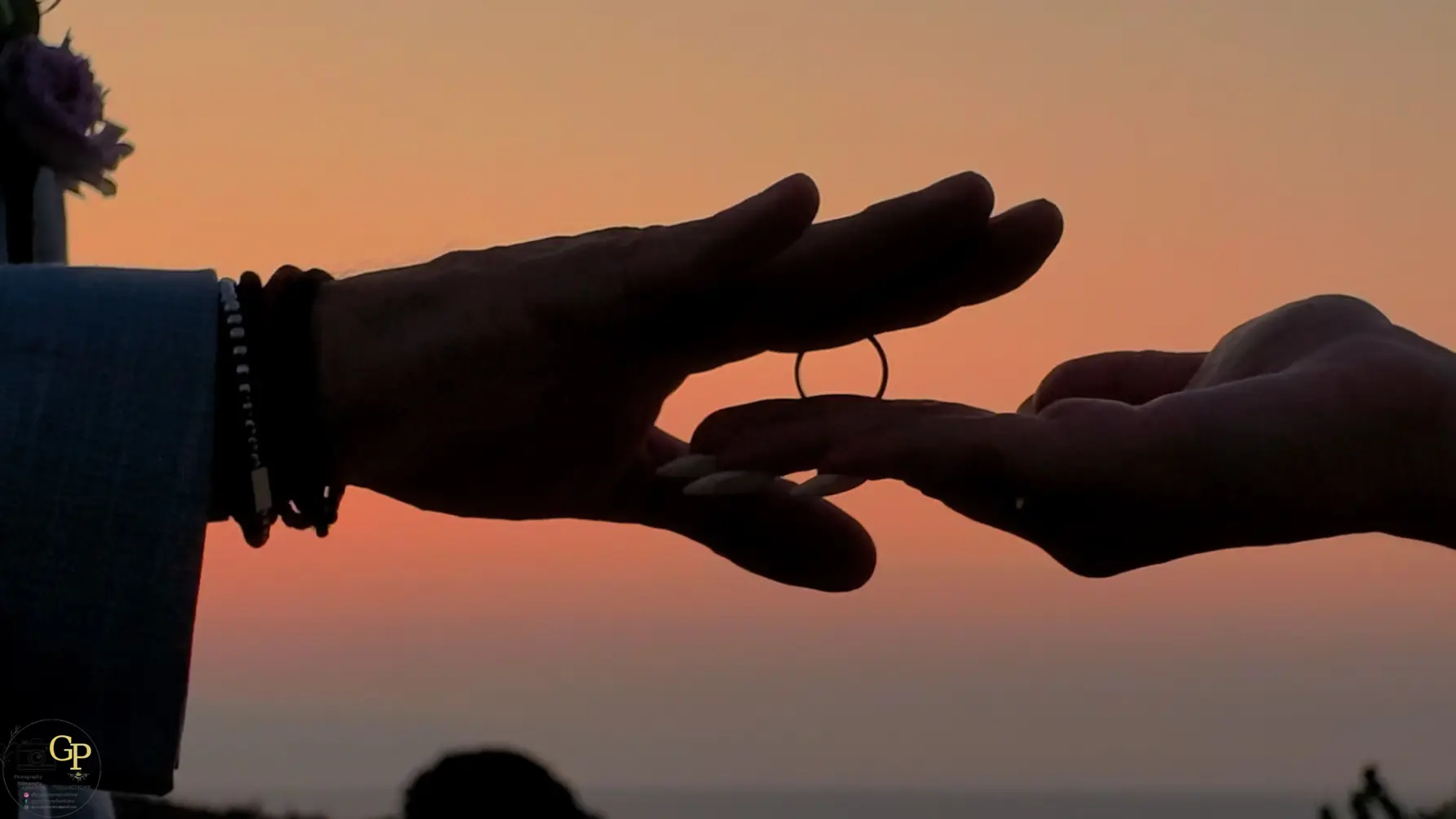 Cinematic wedding photograph of newlyweds exchanging rings at sunset by GP Creta Productions