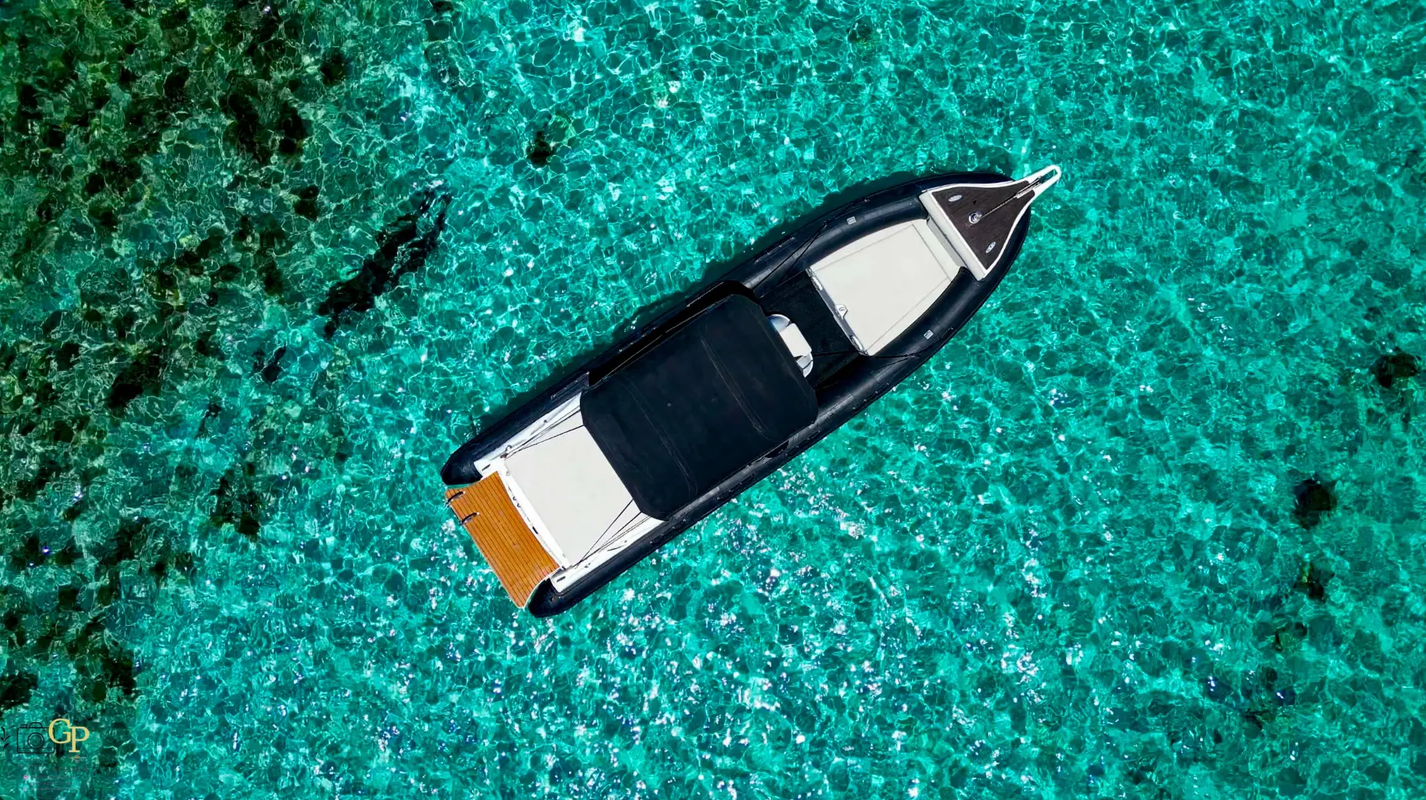 Top-down aerial photograph of a luxury speedboat in turquoise water by GP Creta Productions