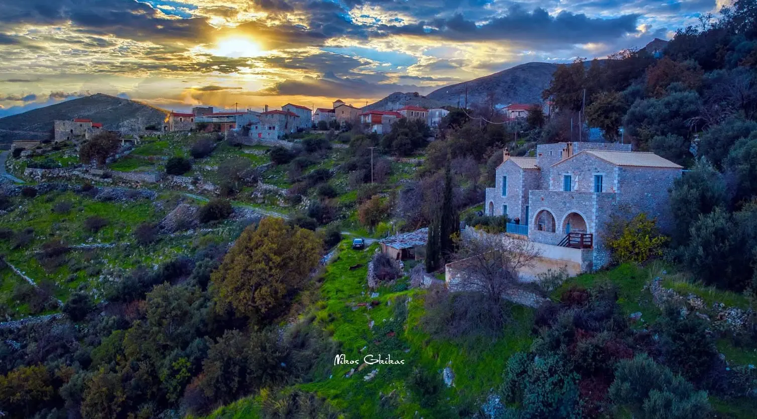 Aerial sunset photograph of a stone village and natural landscape by Nikos Gkikas