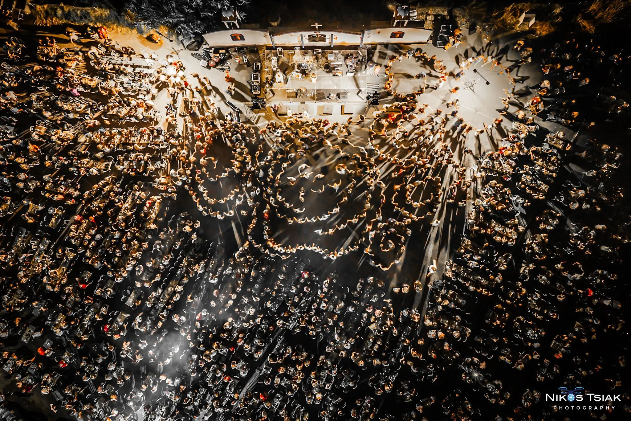 Night-time aerial photograph of a crowded outdoor music event by Nikos Tsiakalakis