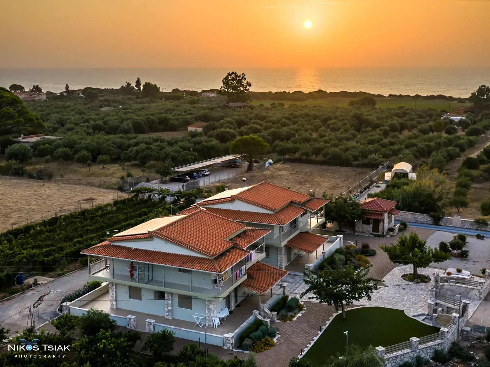 Aerial sunset photograph of a coastal Airbnb property surrounded by olive groves by Nikos Tsiakalakis
