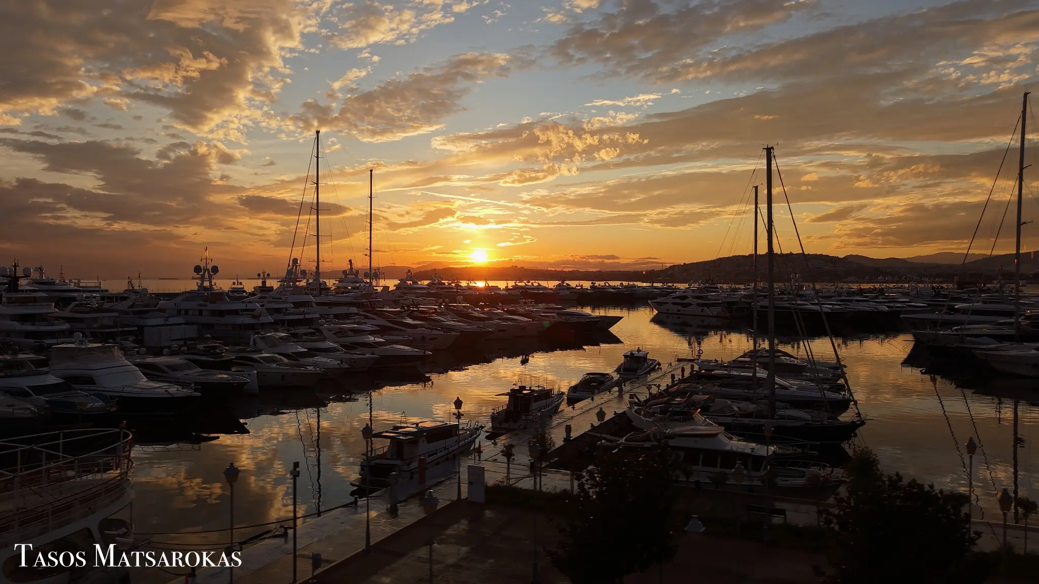 Cinematic aerial sunset photograph of a marina and sailing boats by Tasos Matsarokas