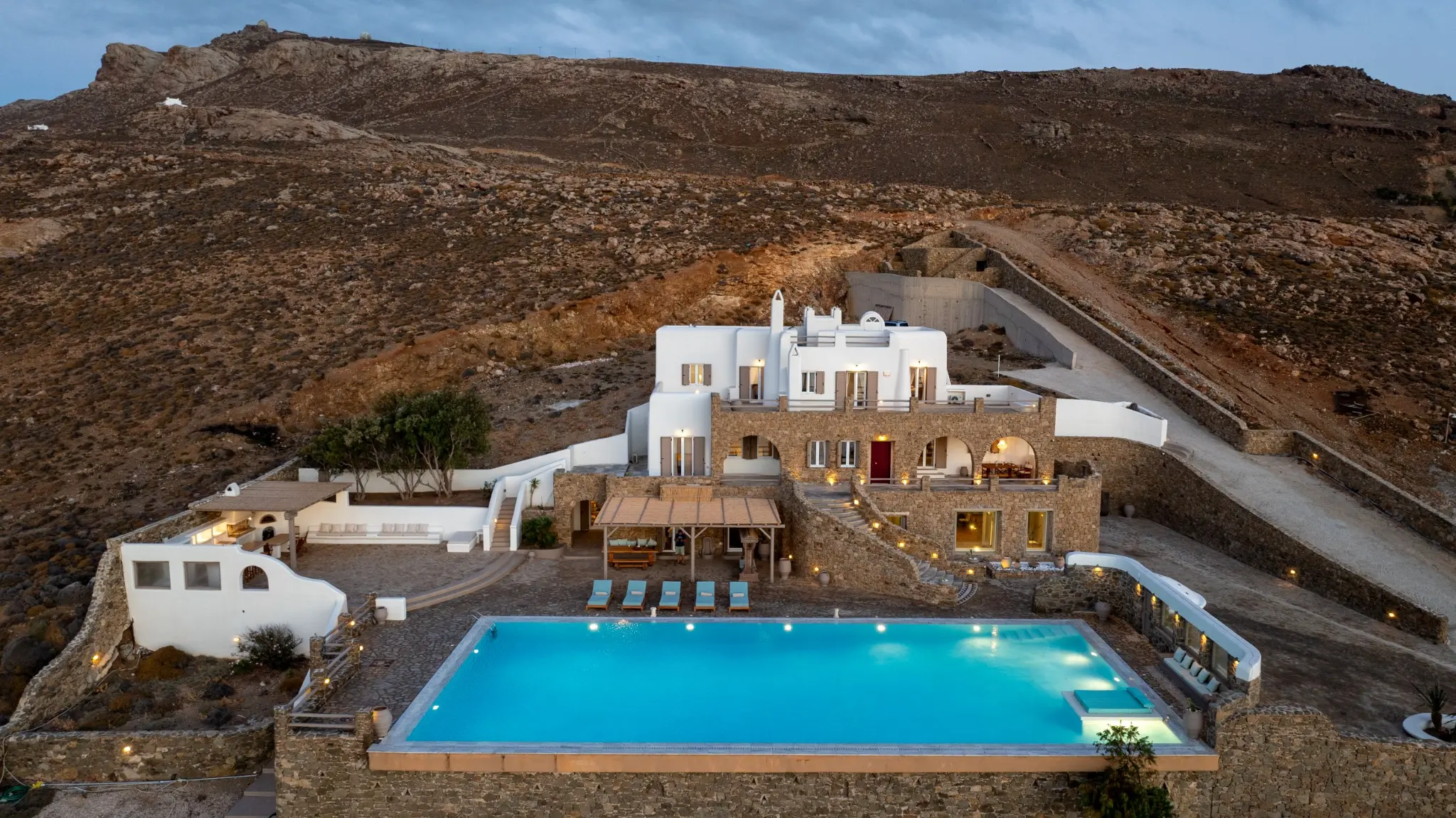 Aerial twilight photograph of a luxury island villa with an illuminated swimming pool by Themistoklis Karantinos